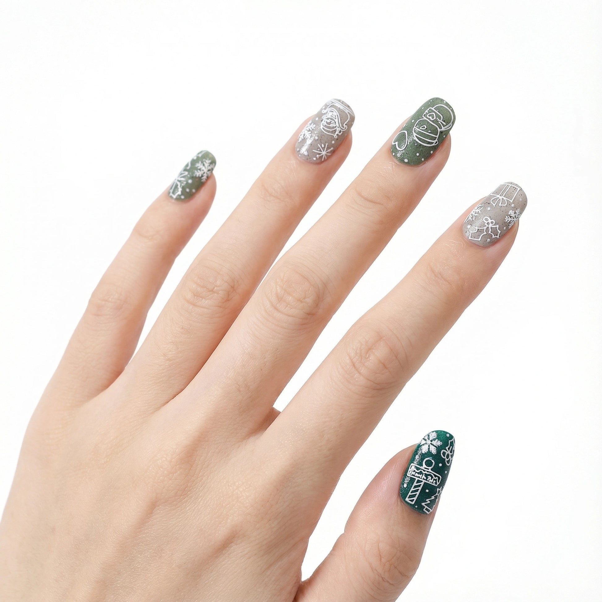 Hand with minimalist christmas line art nail stickers with white outline snowman and gift designs on green nails